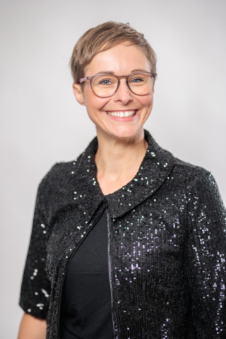 Eine Frau mit Brille und kurzen Haaren lächelt